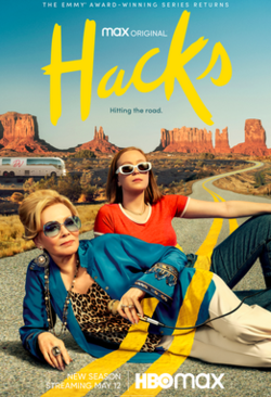 Poster for Hacks featuring two women lounging on a winding desert highway with red rock formations in the background. One wears a blue jacket and sunglasses while the other wears a red top and white pants. A tour bus is seen in the distance.